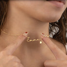 Gold necklace with 'Emma' and a star charm being held by fingers
